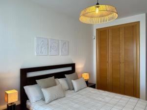 ein Schlafzimmer mit einem Bett mit weißen Kissen und einer Lampe in der Unterkunft Albatros Apartment met-golf-beach in Oliva + 19 Fotos