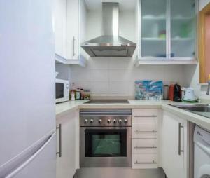 eine Küche mit weißen Schränken und einem Herd mit Backofen in der Unterkunft Albatros Apartment met-golf-beach in Oliva