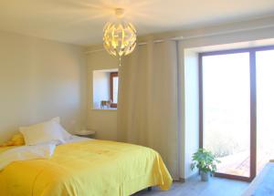 a bedroom with a yellow bed and a chandelier at Le Jardin des 4M in Saint-Régis-du-Coin