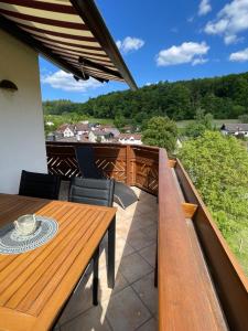a deck with a wooden table and chairs on a balcony at Fewo Anna - ruhig gelegen, mitten in der Natur, unmittelbar am Neckarsteig in Neckarsteinach
