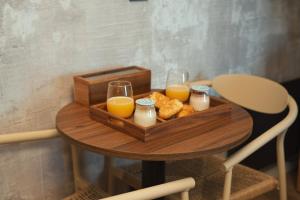 a tray of orange juice and biscuits and glasses of orange juice at Private Hammam & Immersive Cinema - Eden Luxury Suite in Roanne +9 photos
