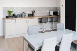 a white kitchen with a table and a microwave at Modern 3 bed duplex apartment in Central Station +8 photos
