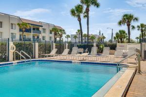 una piscina con sedie e una recinzione con palme di Pool Access Beachfront Condo in Cape Canaveral! a Cape Canaveral
