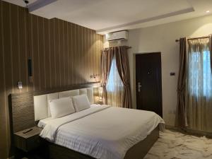 a bedroom with a large bed with white sheets at Tofana Hotel and Suites Mabushi in Abuja