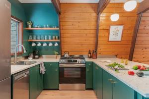 a kitchen with green cabinets and wooden walls at A Frame Hot Tub Couple's Getaway in Island Park