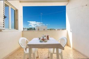 a white table and chairs in a room with a window at Aura apartaments in Torre Lapillo