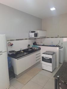 a white kitchen with a stove and a microwave at Apartamento vest unirv in Rio Verde