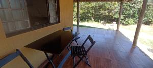 a room with a table and chairs on a porch at Rancho Recanto Verde in Capitólio