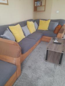 a blue couch with yellow pillows and a coffee table at Millfield caravan site, caravan L6 in Ingoldmells +1 photo