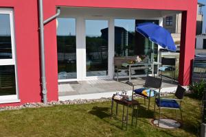 a patio with two chairs and a blue umbrella at Ostseeecke in Kappeln