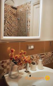 a bathroom sink with a mirror and a vase with flowers at Casaparrinello Maletto Concy in Maletto