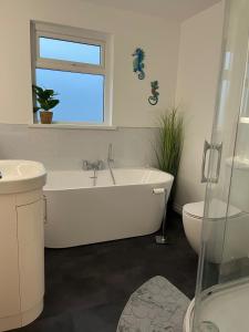 a bathroom with a tub and a sink and a window at Ardnageeha in Doagh