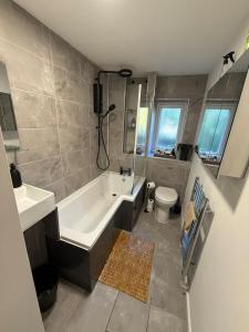 a bathroom with a tub and a sink and a toilet at Spacious New London Apartment! in London