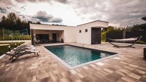 a swimming pool on a patio with chairs and a house at Villa Eden Bihać in Bihać