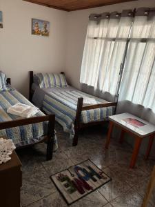 a bedroom with two beds and a table and a window at Alojamiento Santino, en Cataratas del Iguazu in Puerto Iguazú