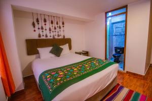 a bedroom with a bed with a colorful blanket on it at Munay Ñusta Cusco in Cusco