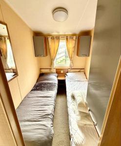 a small room with two beds and a window at 3 Bedroom 8 birth Caravan - Sand Le Mere in Tunstall