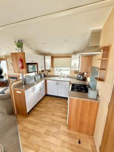 a large kitchen with white cabinets and wooden floors at 3 Bedroom 8 birth Caravan - Sand Le Mere in Tunstall