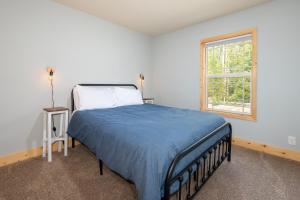 a bedroom with a bed with a blue blanket and a window at 635 Wapit on the FREE shuttle route in Fraser