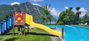 a playground with a slide next to a pool at Tropical Art Apartment in Bissone