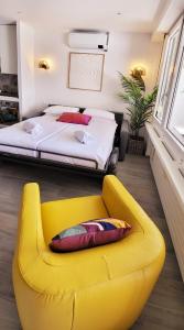 a yellow chair in a bedroom with a bed at Tropical Art Apartment in Bissone +39 photos