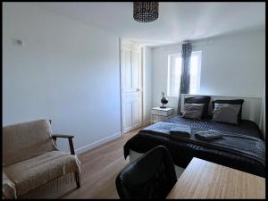 een slaapkamer met een bed, een bank en een stoel bij SQ Appart-ment in Saint-Quentin