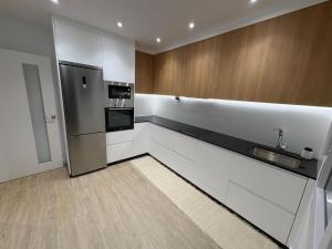 a kitchen with white cabinets and a stainless steel refrigerator at Casa Galbán in Vilagarcia de Arousa