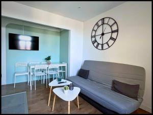 een woonkamer met een bank en een klok aan de muur bij SQ Appart-ment in Saint-Quentin