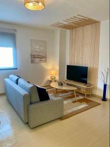 a living room with a blue couch and a tv at Refugio del Atlántico in El Puerto de Santa María