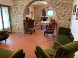 a living room with green furniture and a stone wall at Podere Piccini with pool in Val d'Orcia-Tuscany in Piancastagnaio