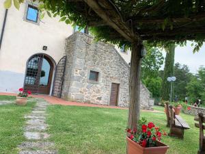 a stone building with a porch and flowers in a yard at Podere Piccini with pool in Val d'Orcia-Tuscany in Piancastagnaio