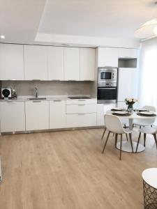 a kitchen with white cabinets and a table with chairs at Suite Estébanes in Zaragoza