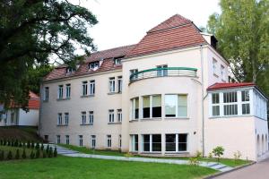 a large white building with a red roof at Uzdrowisko Polczyn Borkowo in Połczyn-Zdrój