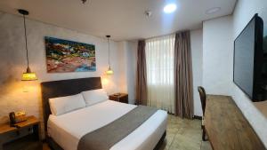 a hotel room with a bed and a television at Casa del Hidalgo Hotel Cali Centenario in Cali +55 photos