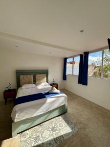 a bedroom with a large bed and two windows at Alojamiento para ocho con alberca Casa A in Mérida +5 photos
