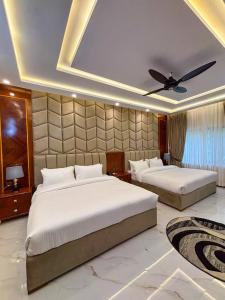 a bedroom with two beds and a ceiling fan at Ariston Suites in Islamabad