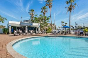 a swimming pool at a resort with chairs and palm trees at Best Western Cocoa Beach - Port Canaveral in Cocoa Beach