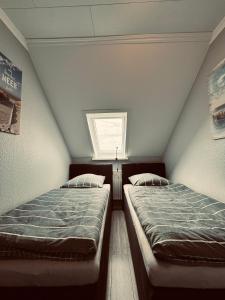 two twin beds in a room with a window at Apartment 4 - Haus Heinke am Deich in Friedrichskoog