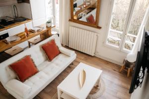 a living room with a white couch and a table at Escapade à 2 ou en petit groupe Appartement tout équipé Quartier résidentiel calme RER direct Parfait pour télétravail et détente in Saint-Maur-des-Fossés