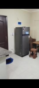 a kitchen with a stainless steel refrigerator and a stool at وحدة للإيجار في إحدى قرى الساحل الشمالي المميزة in Dawwār Abū Maḩrūs +3 photos