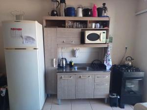 a small kitchen with a refrigerator and a microwave at Apart próximo a Unimed, Catedral e HSA de 2 quartos com 2 AR, mini-Academia e garagem no Centro-sul in Santo Ângelo