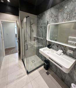 a bathroom with a shower and a sink and a mirror at New Luxury CBD Apartments in Dunedin