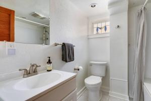 a white bathroom with a sink and a toilet at Stylish Daylight Basement Apartment- Patio + Grill in Seattle +16 photos