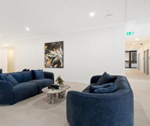 布里斯班Queen's Wharf Residences的客厅里有两张蓝色沙发和一张桌子