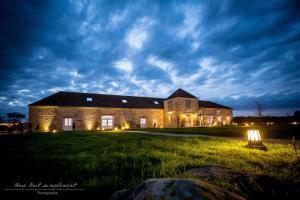 un gran edificio de ladrillo en un campo por la noche en Yourte Nomade-Lodge, en La Chapelle-Gauthier