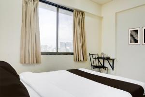 a bedroom with a bed and a table and a window at Hotel O Destination 41 in Pune +38 photos