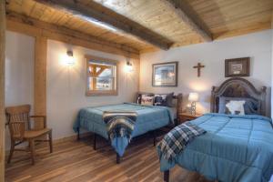 a bedroom with two beds and a cross on the wall at Homestake Cabin in Creede