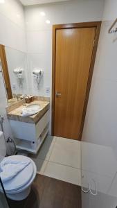a bathroom with a toilet and a wooden door at Flat Lindíssimo de 2qts uma esquina do Flamboyant Shopping 206 in Goiânia +10 photos
