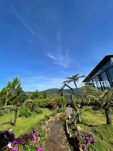 un jardin avec des fleurs roses et un bâtiment dans l'établissement Săn Mây Coffee and Homestay Măng Đen, à Kon Von Kla