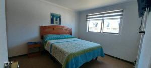 een kleine slaapkamer met een bed en een raam bij Alquiler House in Puerto Montt